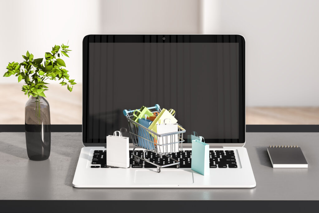 Close up of desk with laptop and tiny shopping carts on keaybord. Blurry wall background. Online shopping and commerce concept. 3D Rendering