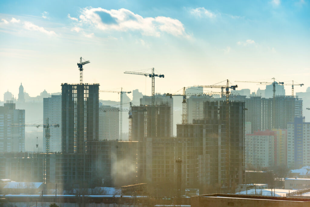 Landscape sunset in the city with blue sky, sun and industrial cranes