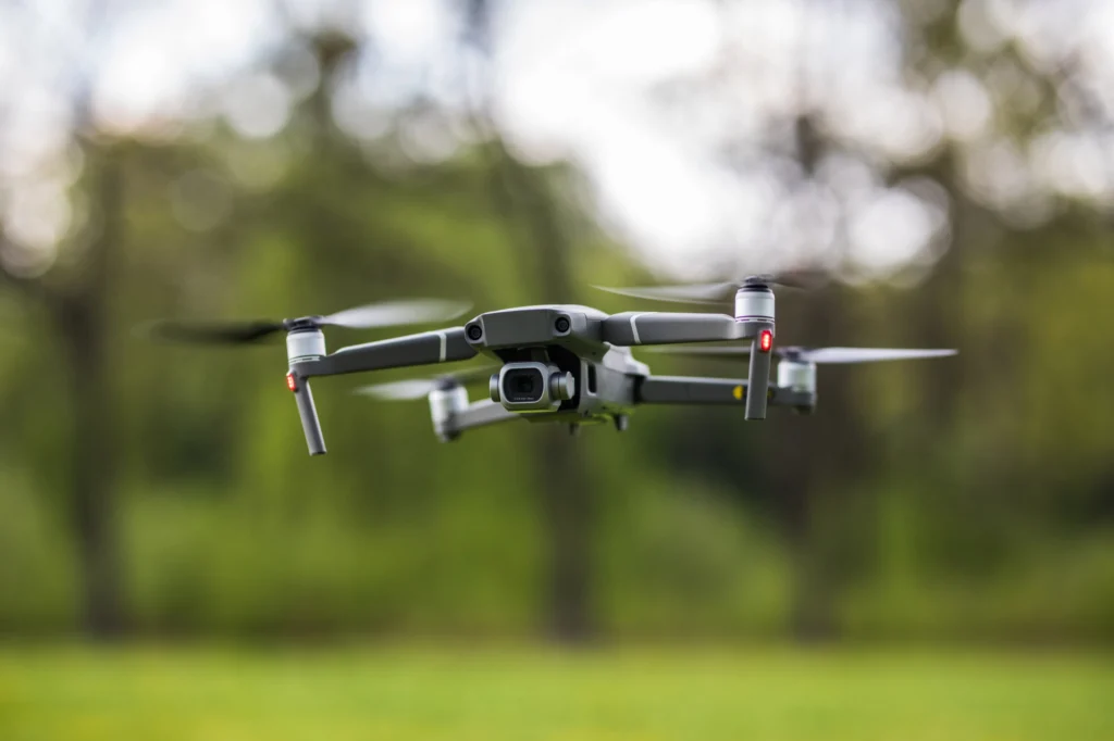 Quadcopter flying on a clear sunny green day background with nice lens flare.