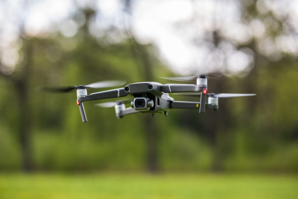 Quadcopter flying on a clear sunny green day background with nice lens flare.
