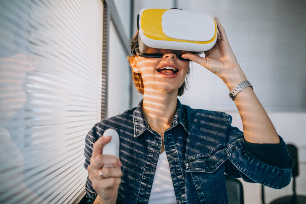 Young woman wearing VR glasses and playing virtual game using remote