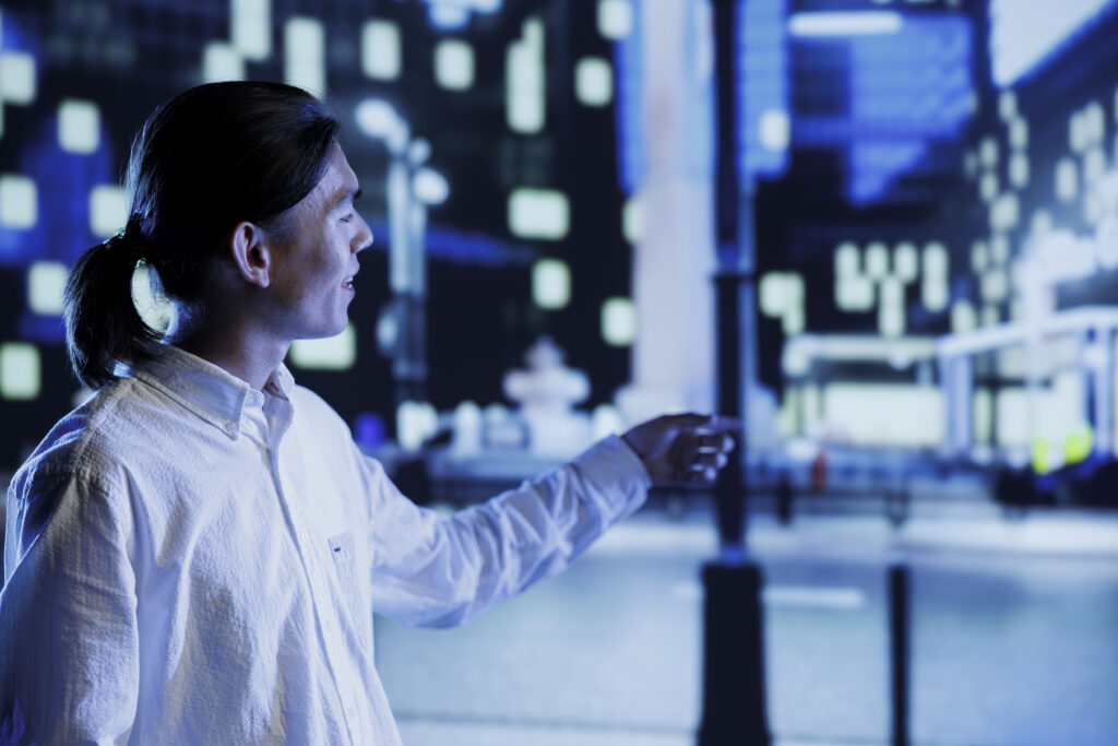 Relaxed asian man wandering around city streets at night, looking around to surrounding skyscrapers in metropolitan urban setting. Businessman leaving work, taking a walk outside empty town